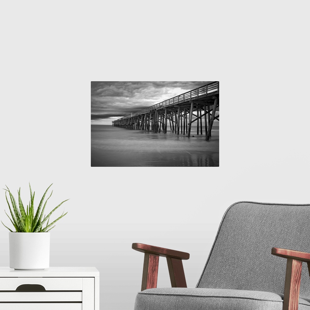 A modern room featuring A black and white photograph of a long pier jetting out over the ocean.