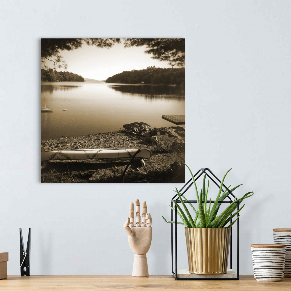 A bohemian room featuring Sepia toned photograph of a canoe resting on the shores of a lake in an idyllic wilderness scene.
