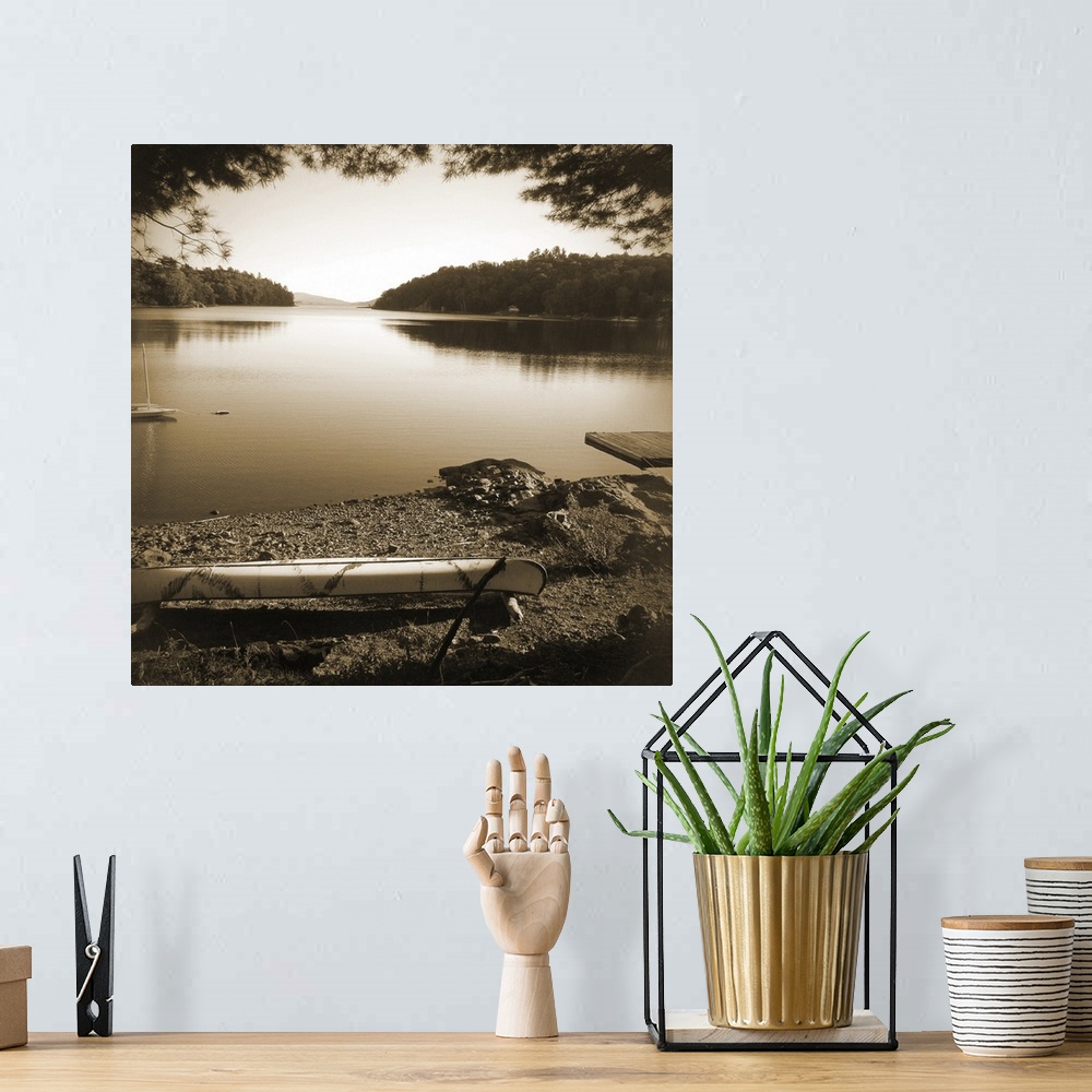 A bohemian room featuring Sepia toned photograph of a canoe resting on the shores of a lake in an idyllic wilderness scene.