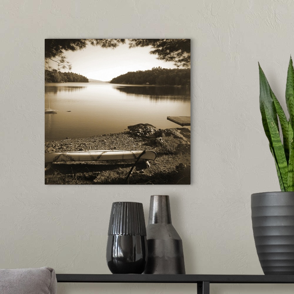 A modern room featuring Sepia toned photograph of a canoe resting on the shores of a lake in an idyllic wilderness scene.
