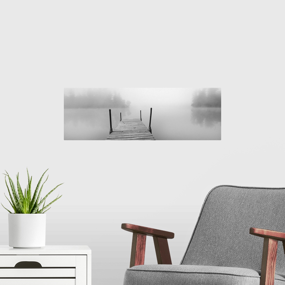 A modern room featuring A black and white photograph of a dock stretching out over a foggy lake in an idyllic setting.