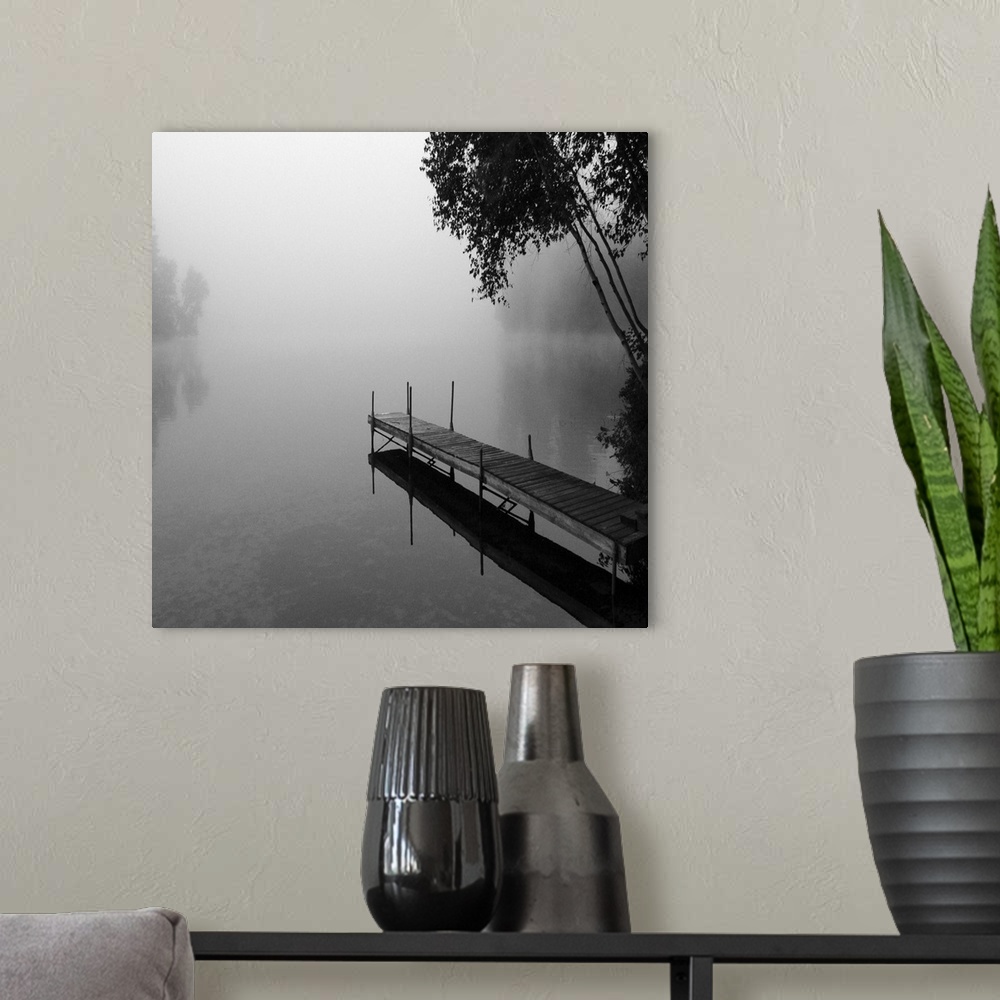 A modern room featuring Black and white photograph of a dock jetting out over a foggy lake in the countryside.