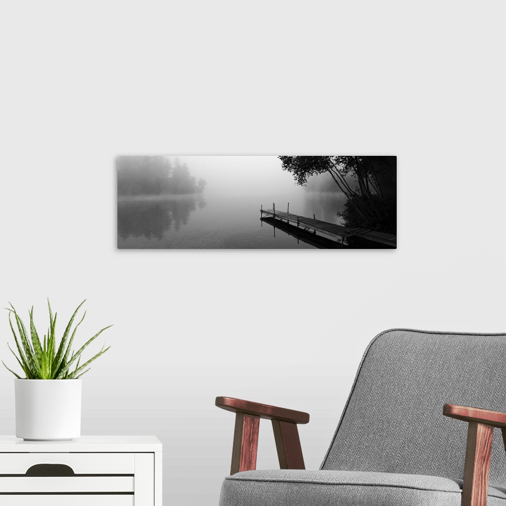 A modern room featuring A black and white photograph of a dock stretching out over a foggy lake in an idyllic setting.