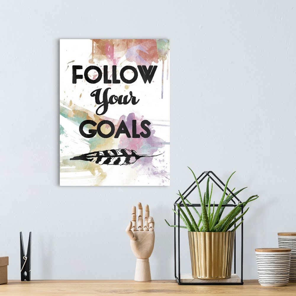 A bohemian room featuring A watercolor painting with the phrase ?Follow Your Goals? in black with a feather underneath and ...