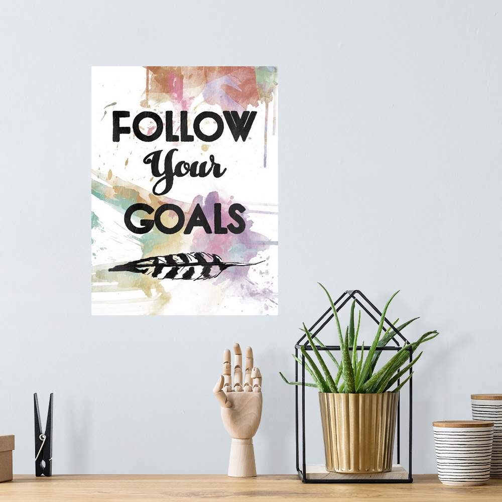 A bohemian room featuring A watercolor painting with the phrase ?Follow Your Goals? in black with a feather underneath and ...