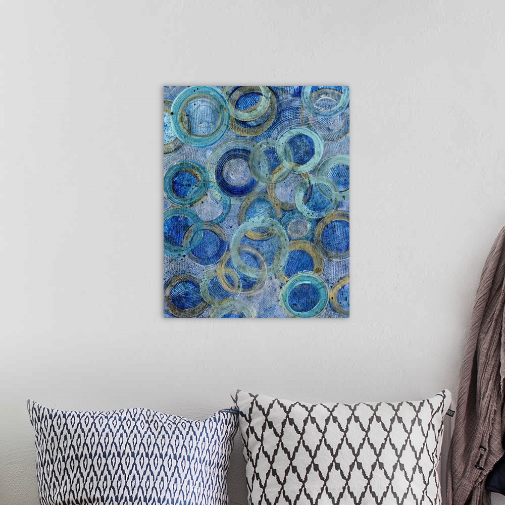 A bohemian room featuring Contemporary abstract artwork of several overlapping rings in blue and gold tones.