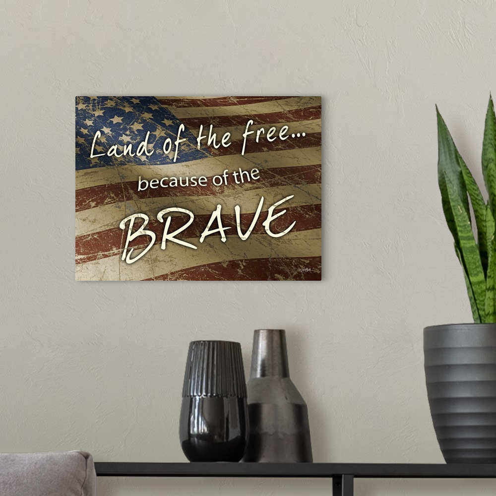 A modern room featuring "Land of the Free Because of the Brave" on a rustic waving American flag.