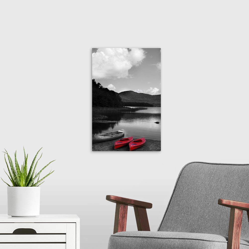 A modern room featuring Black and white photograph with two bright red kayaks next to a canoe, resting on the shore of a ...