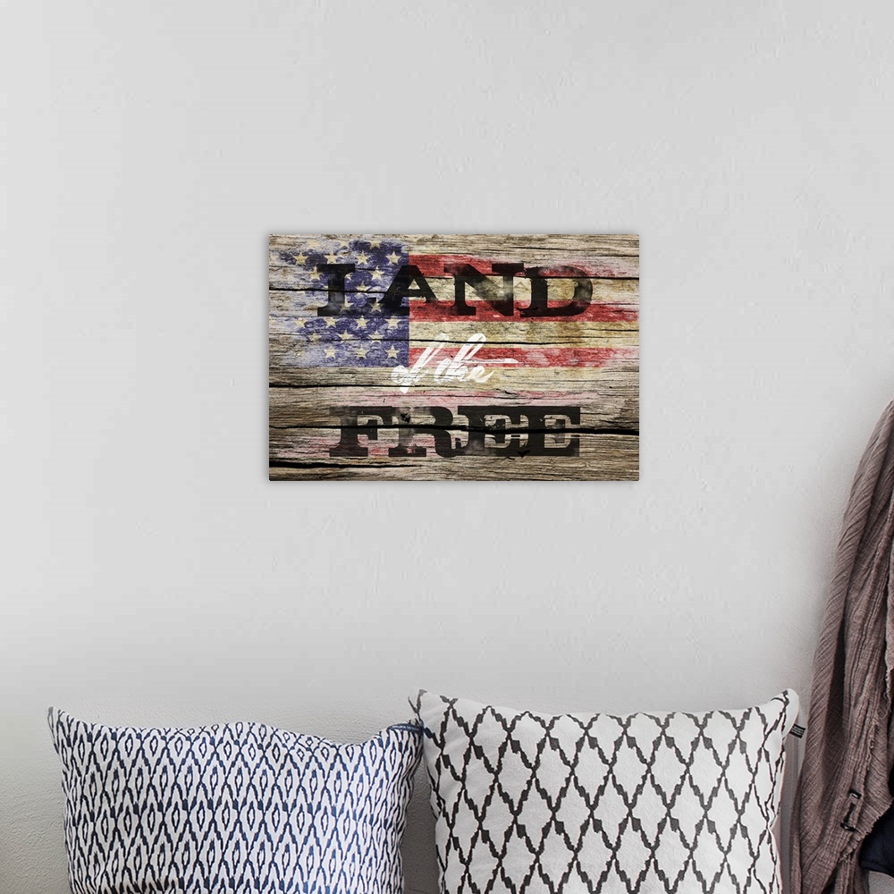 A bohemian room featuring The phrase ?Land of the Free? placed on a distressed wooden panel background with an American fla...