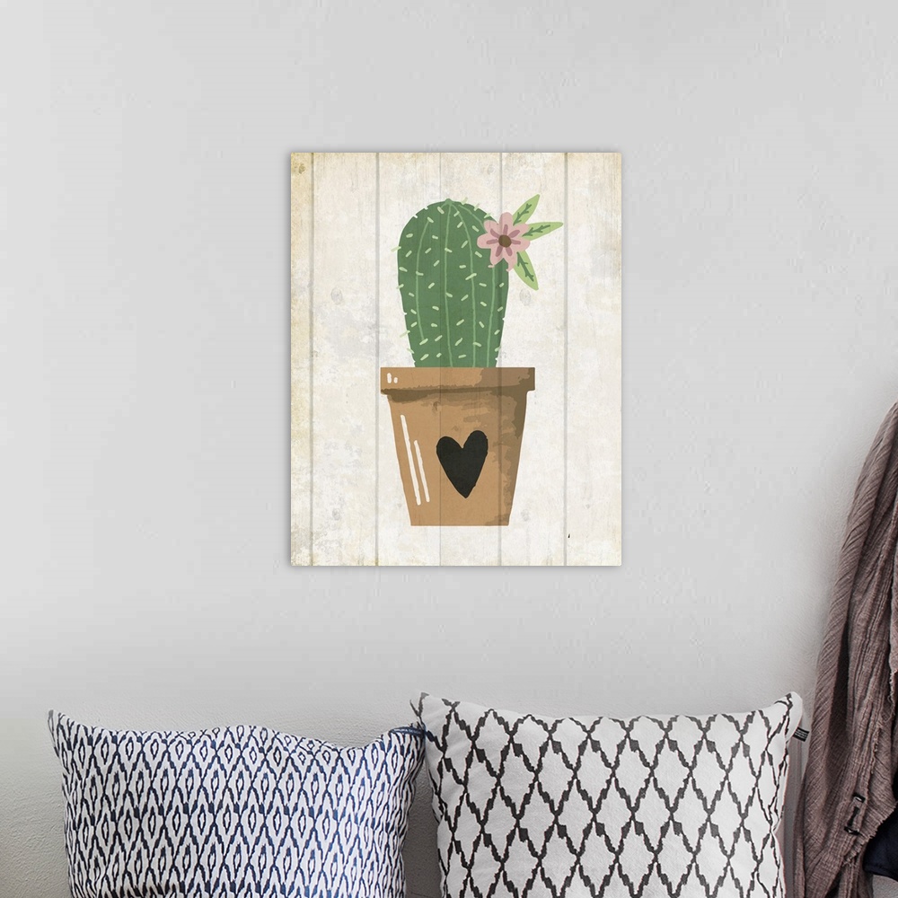 A bohemian room featuring A painting of a cactus with a flower in a clay pot with a heart painted on it placed on a wooden ...