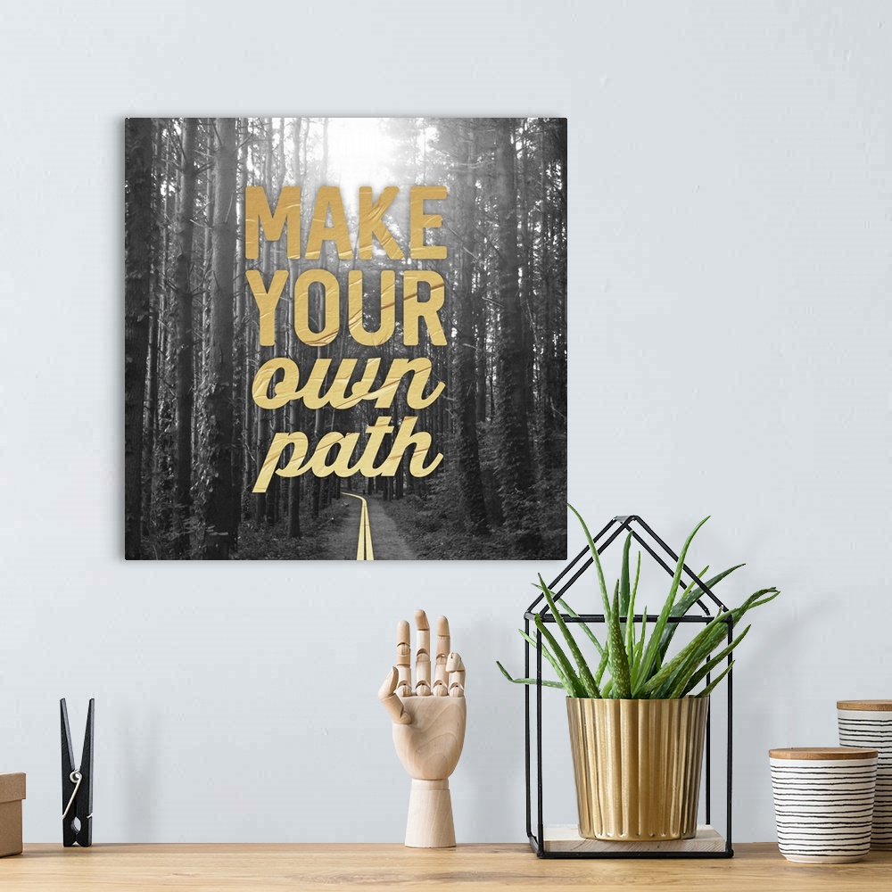 A bohemian room featuring A black and white square photograph of a path in the woods with the phrase ?make your own path? p...