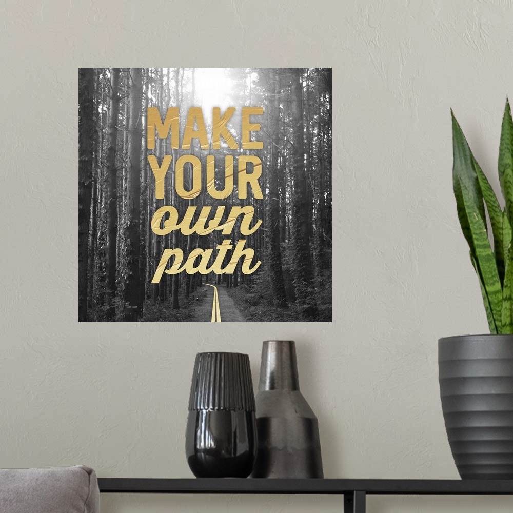A modern room featuring A black and white square photograph of a path in the woods with the phrase ?make your own path? p...