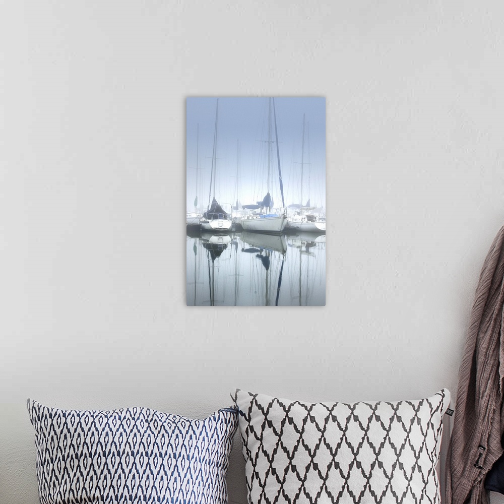 A bohemian room featuring Several sailboats on calm waters in a harbor on a foggy morning.