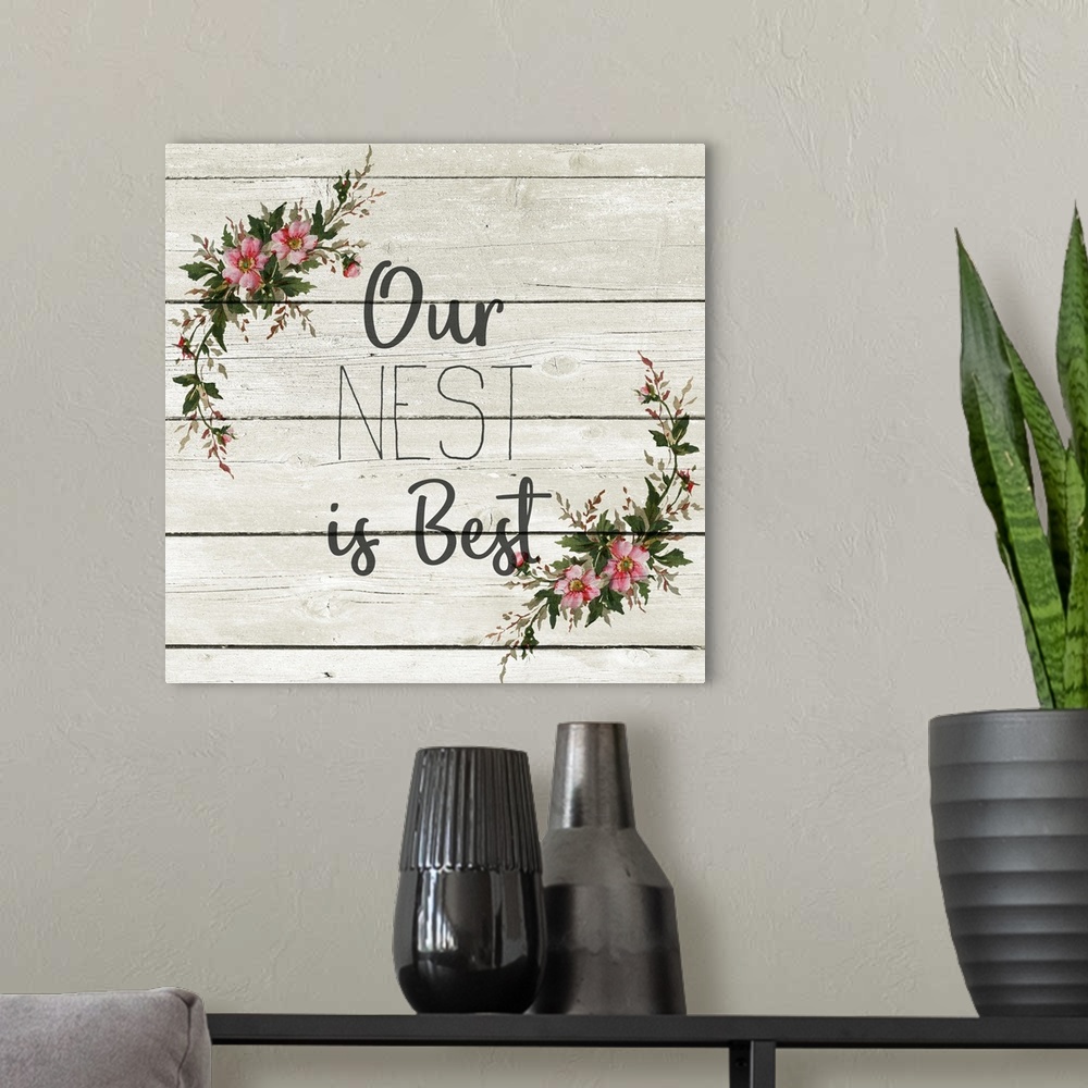 A modern room featuring "Our Nest is Best" with a wreath of flowers on a gray wood plank background.