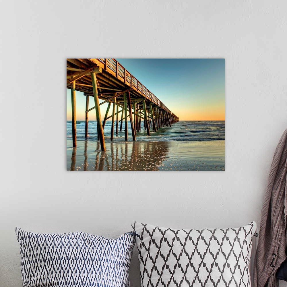 A bohemian room featuring A photograph of a long pier jetting out over the ocean. Sunlight glowing over the horizon as the ...