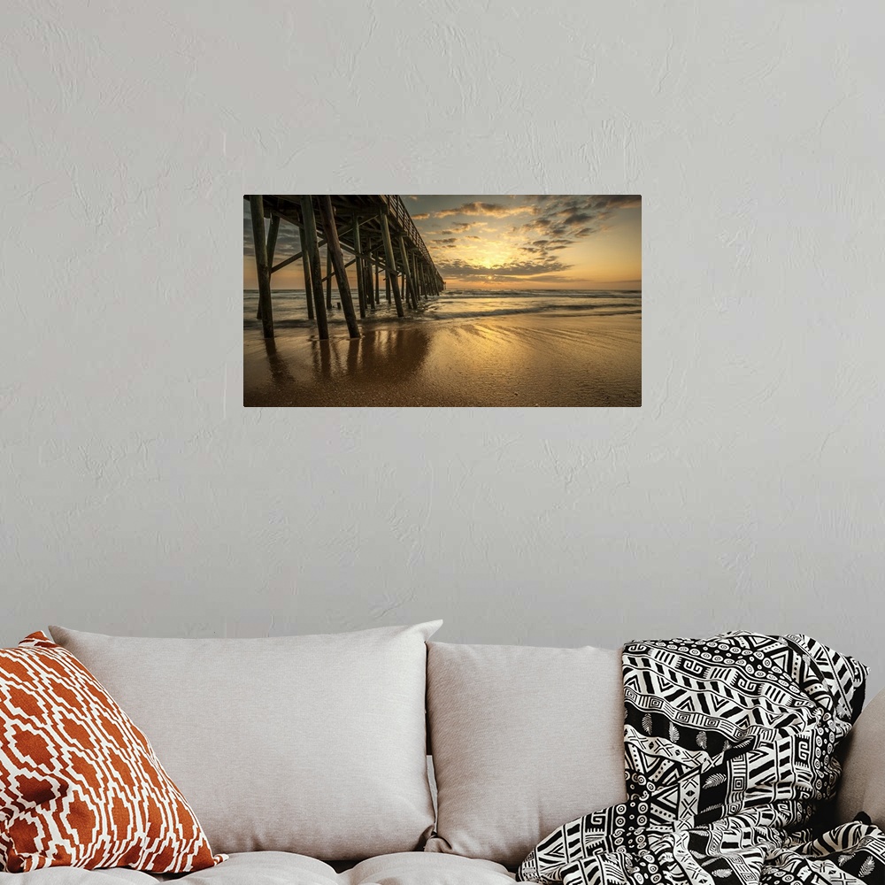 A bohemian room featuring A photograph of a long pier jetting out over the ocean. Sunlight bathing the sky in an orange glo...