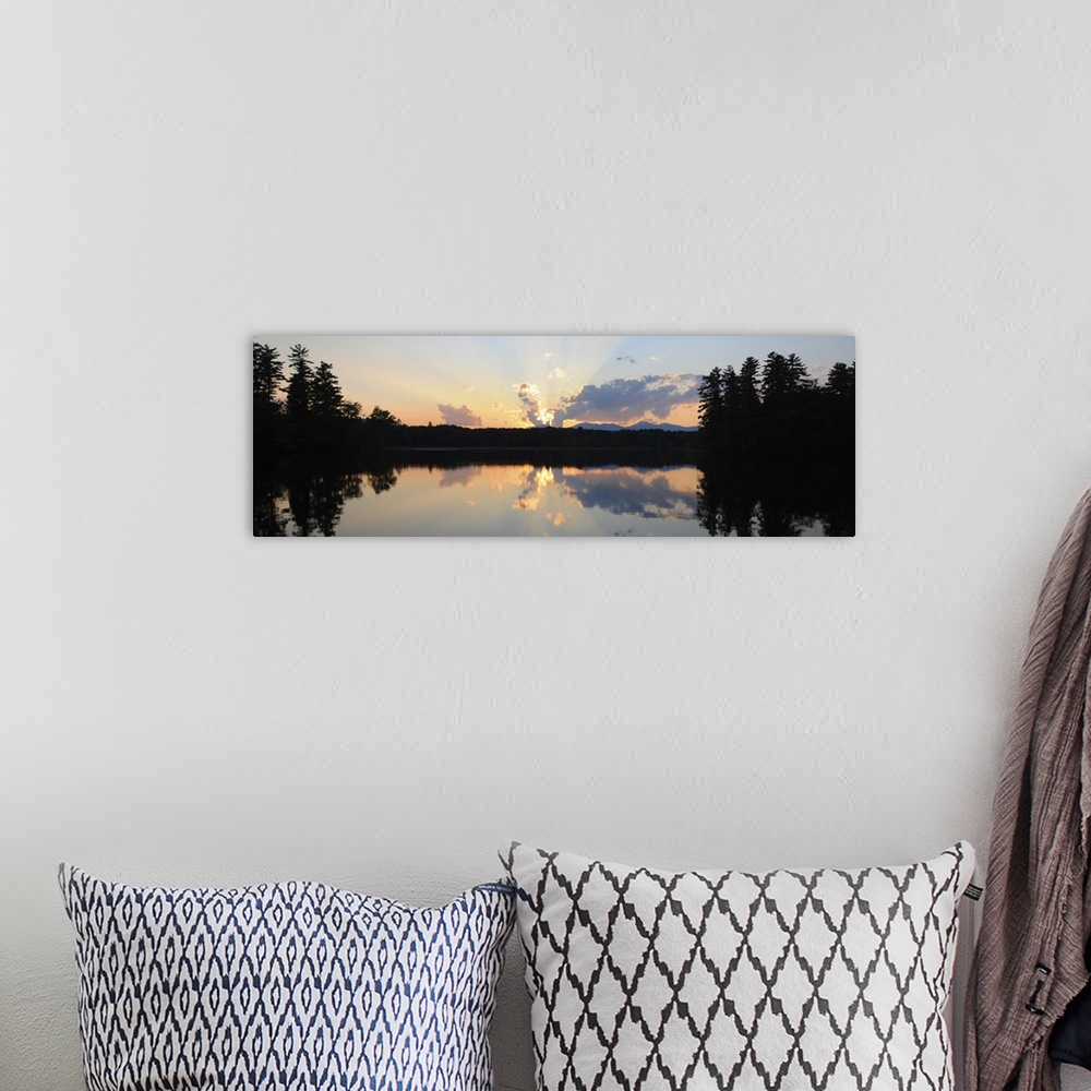 A bohemian room featuring A photograph of a beautiful sun rising over an idyllic landscape. Being reflected in a lake, whil...