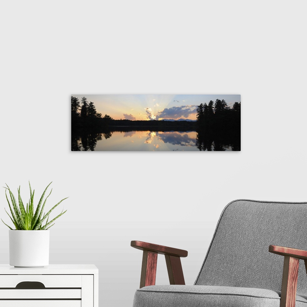 A modern room featuring A photograph of a beautiful sun rising over an idyllic landscape. Being reflected in a lake, whil...
