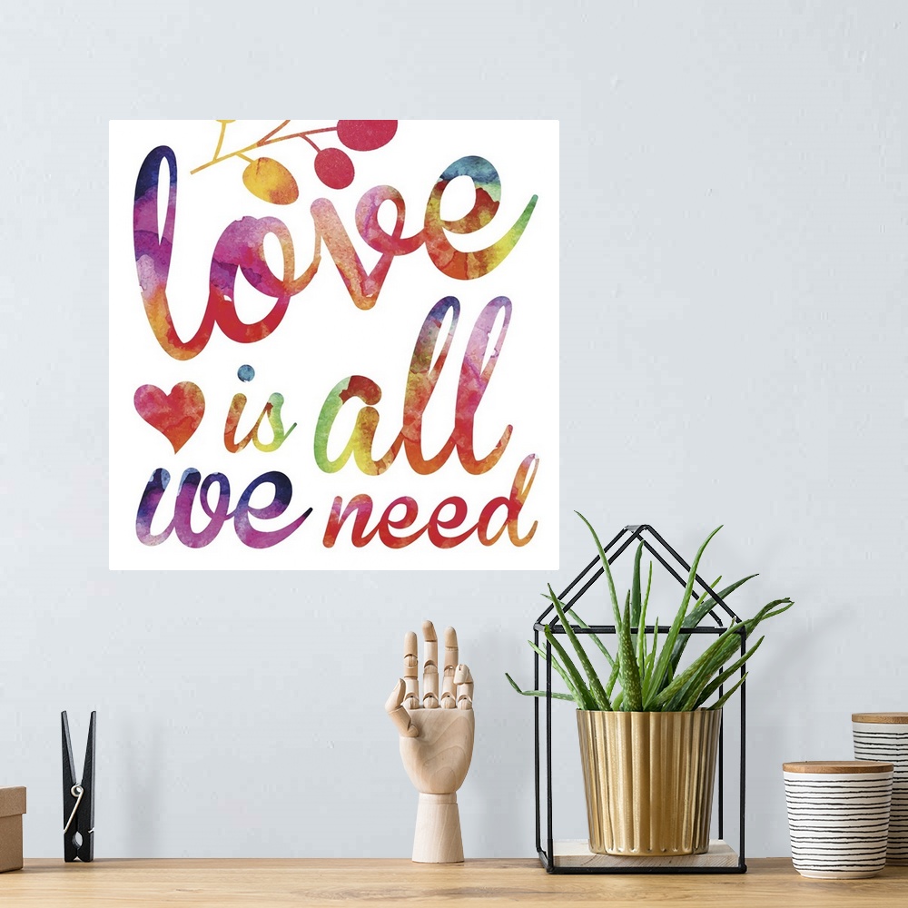 A bohemian room featuring "Love is all we need" in script lettering in  rainbow watercolors.