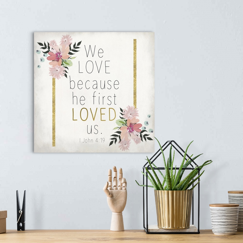 A bohemian room featuring Bible verse 1 John 4:19 with gold stripes and pink flowers.