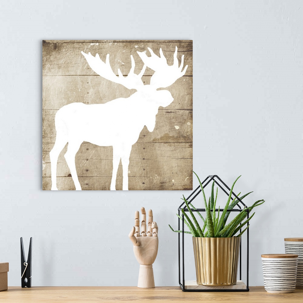 A bohemian room featuring A white silhouette of a moose painted on a wood background.
