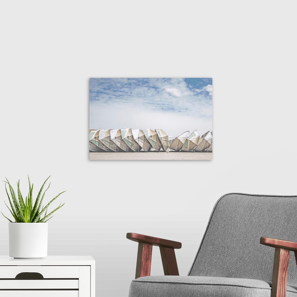 A modern room featuring A fine art photograph of a row of identical small boats leaned against each other, with a very co...