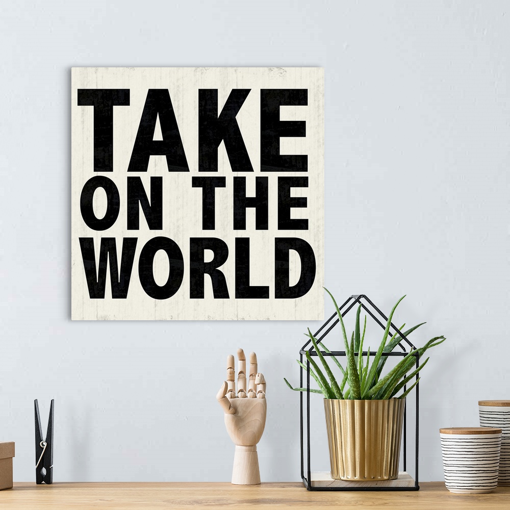 A bohemian room featuring "Take On The World" in bold lettering over a weathered white background.