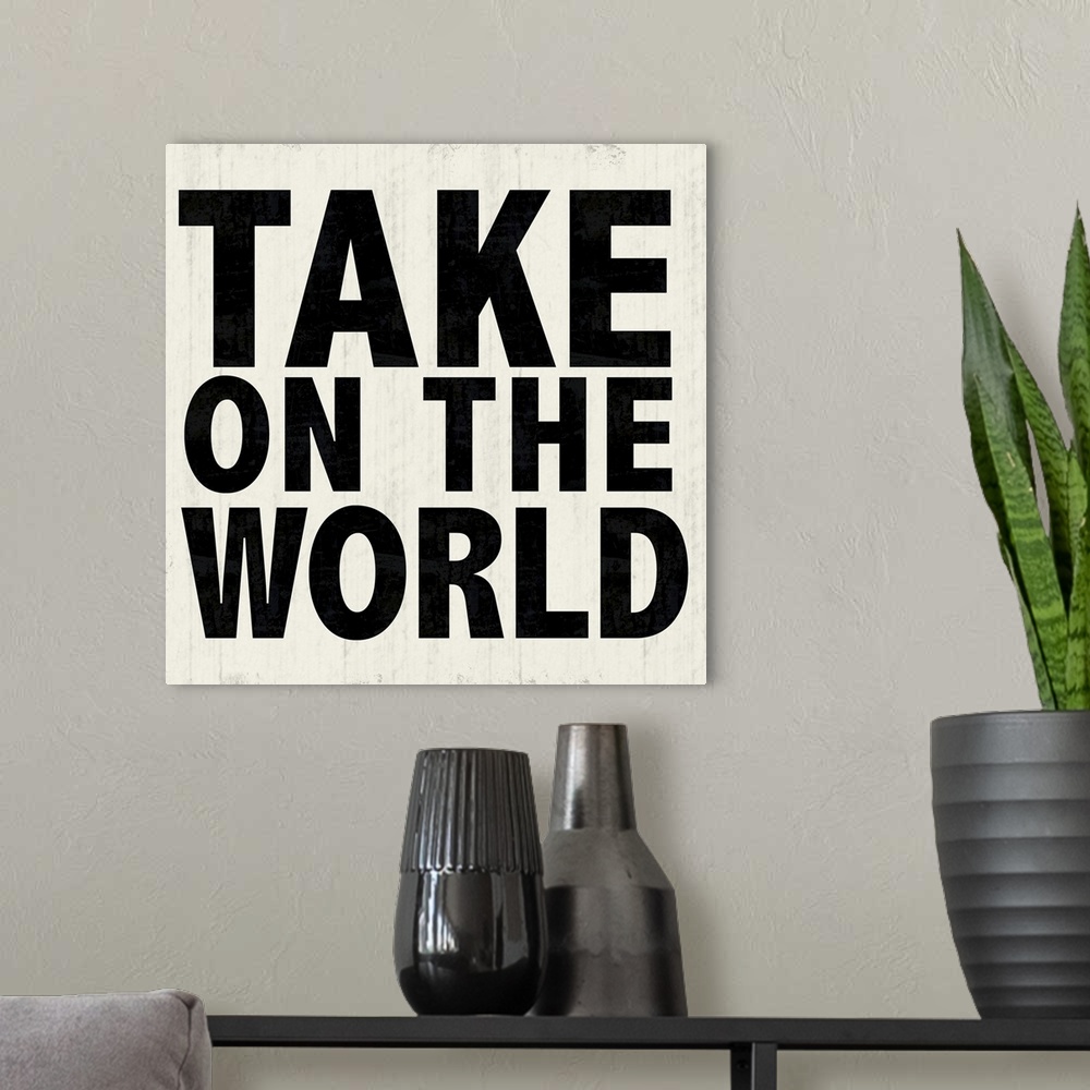 A modern room featuring "Take On The World" in bold lettering over a weathered white background.
