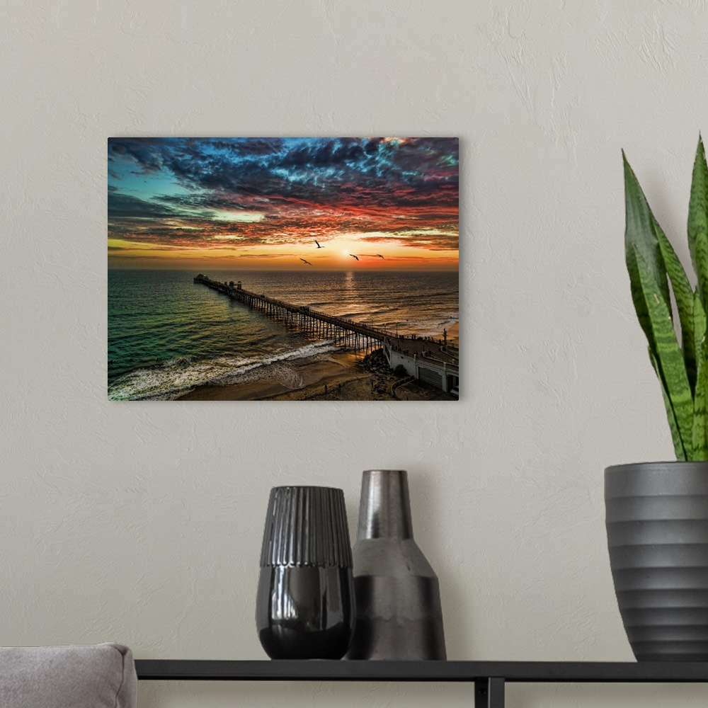 A modern room featuring Pelicans glide past a dramatic and colorful sunset near the Oceanside Pier, Oceanside, California...
