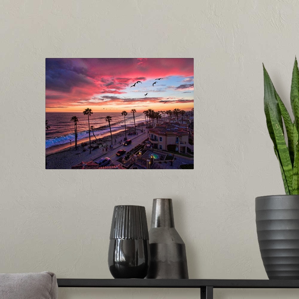 A modern room featuring Colorful sunset with seabirds passing over the coastline in Oceanside, California, USA.