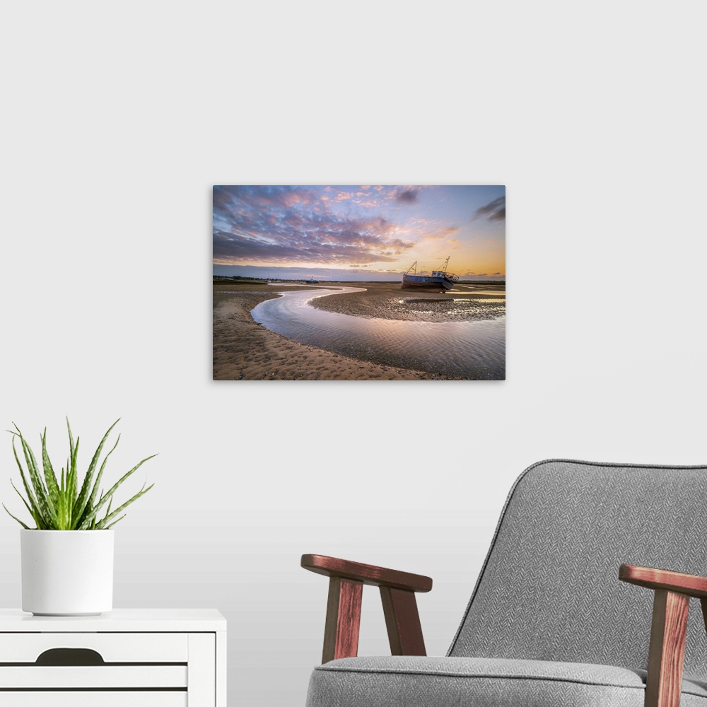 A modern room featuring A fishing boat next to a winding river through the sand during sunset at Mow Creek at Brancaster ...