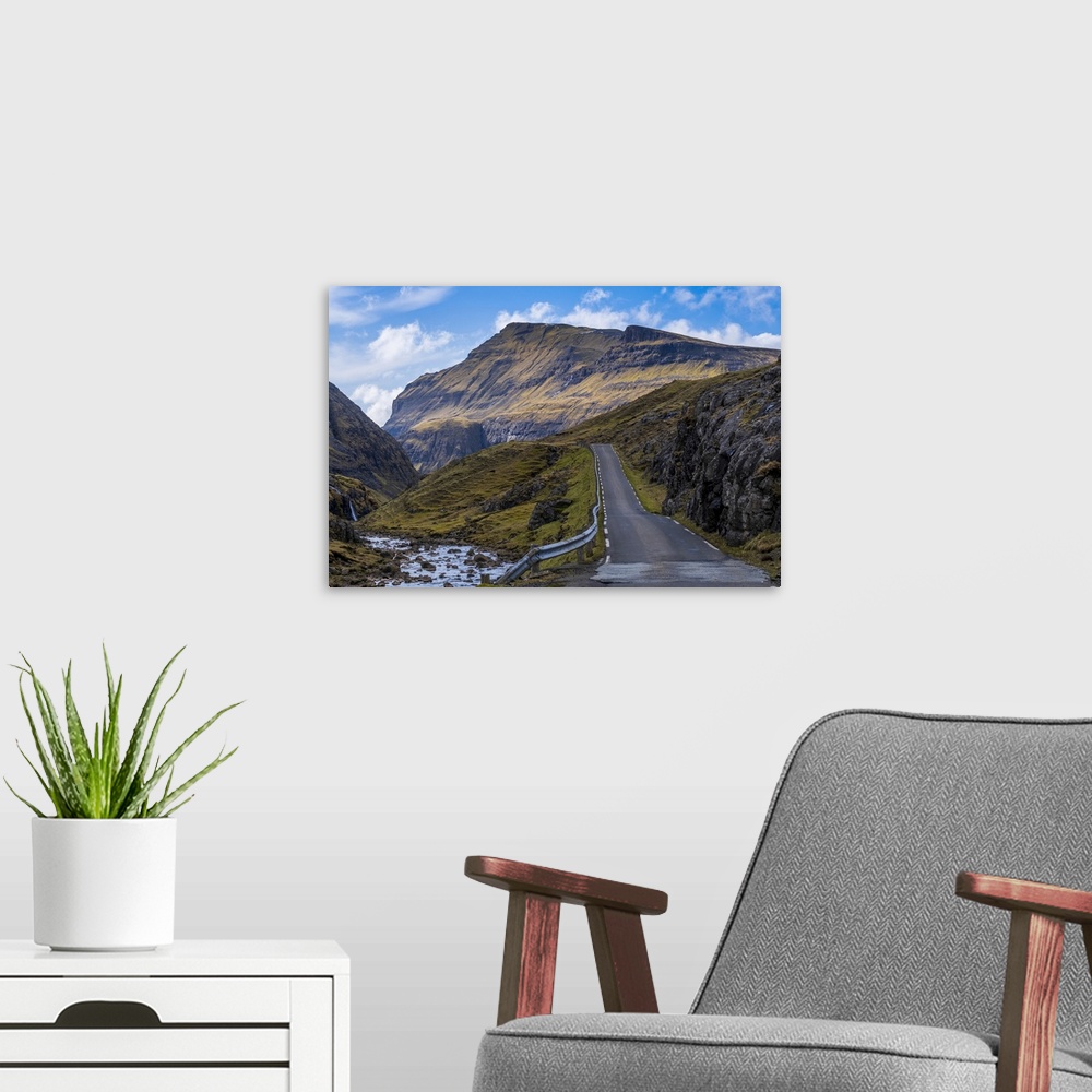 A modern room featuring A scenic empty straight uphill road leading to Saksun on the Faroe Islands.