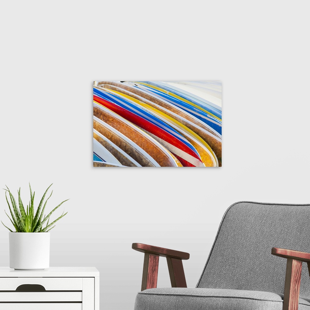 A modern room featuring A stack of colourful longboard surfboards placed on the beach,; Waikiki, Oahu, Hawaii, United Sta...