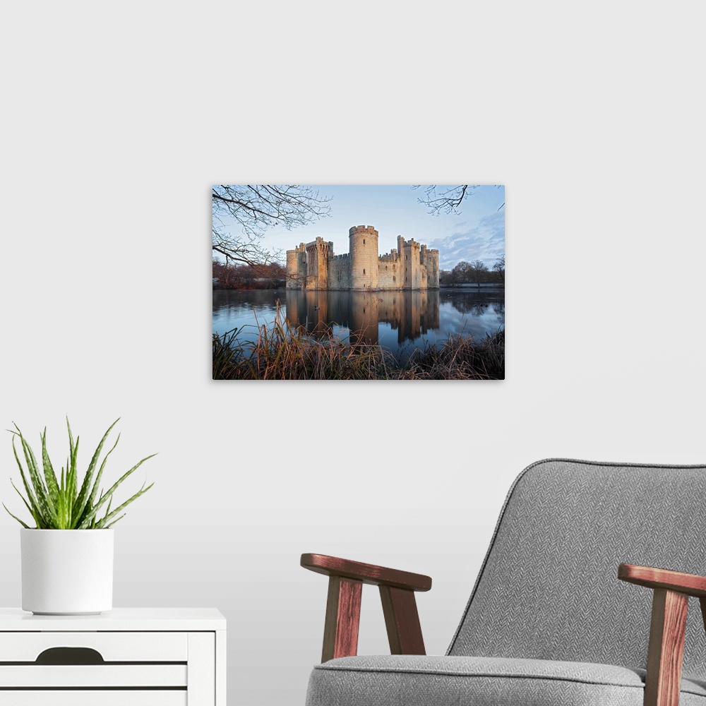 A modern room featuring A view of Bodiam Castle with reflection in the water.