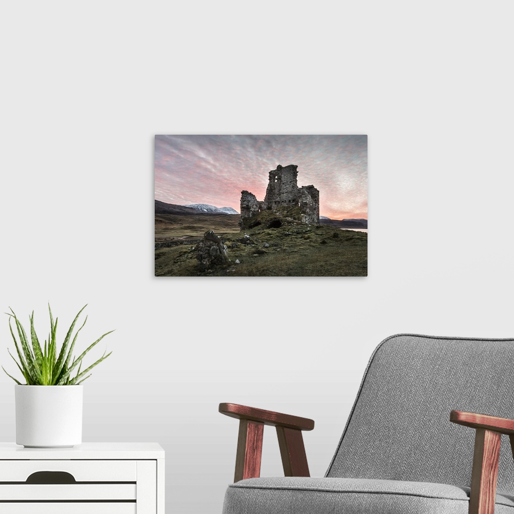 A modern room featuring A view toward Ardvreck castle at sunset.