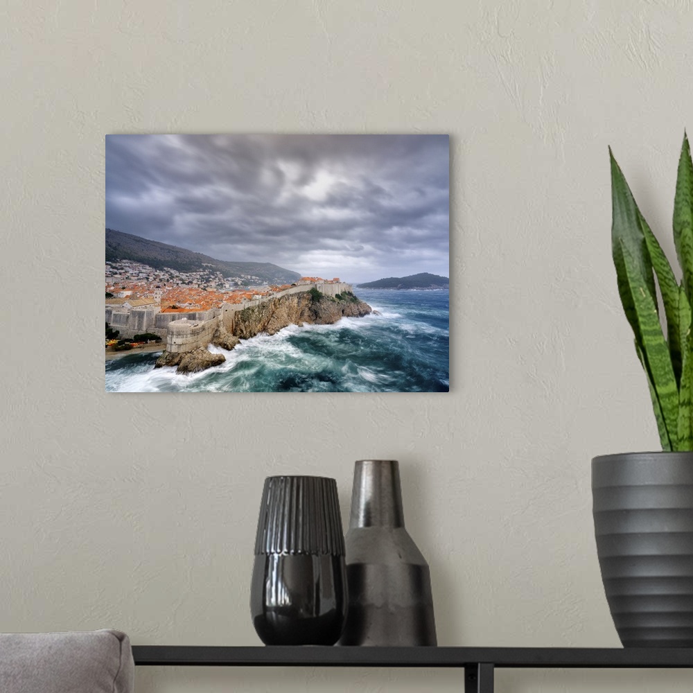 A modern room featuring A view towards Dubrovnik Old Town with stormy seas below the city walls.