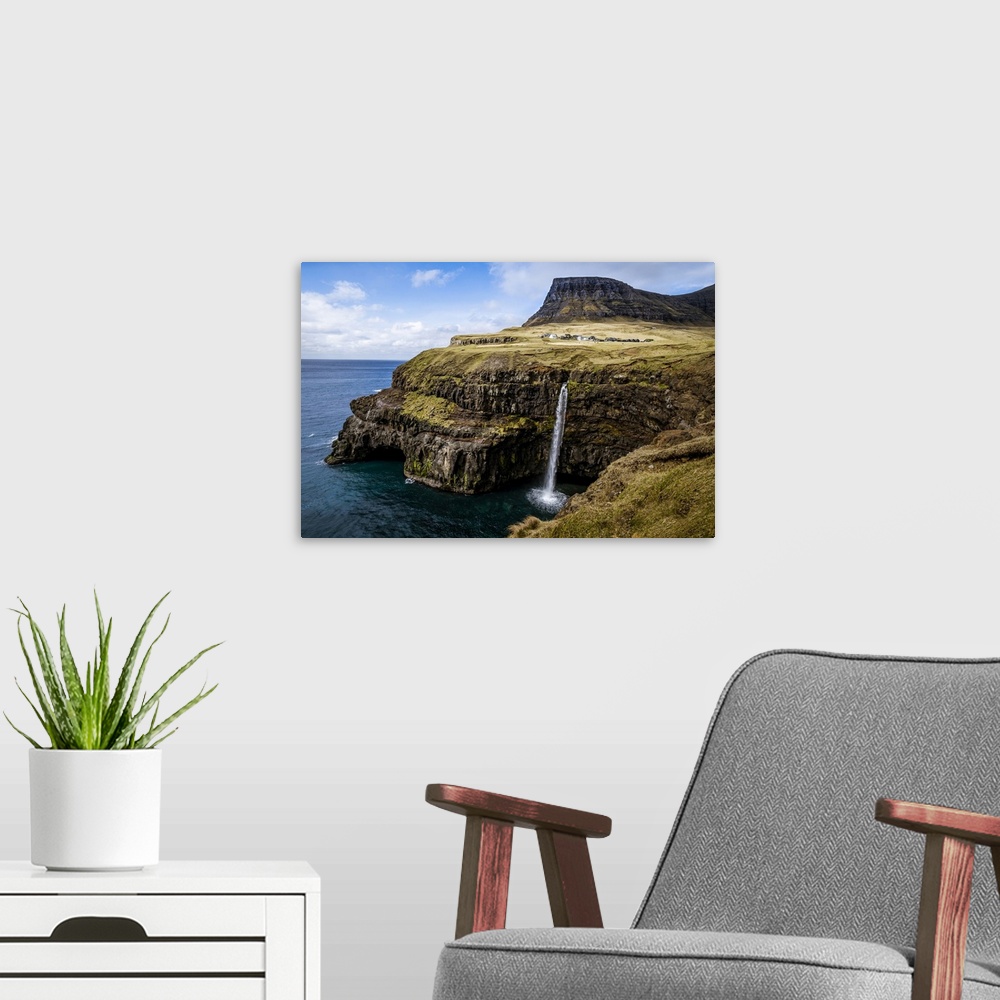 A modern room featuring A waterfall cascades down a dramatic rockface on the Faroe Islands.