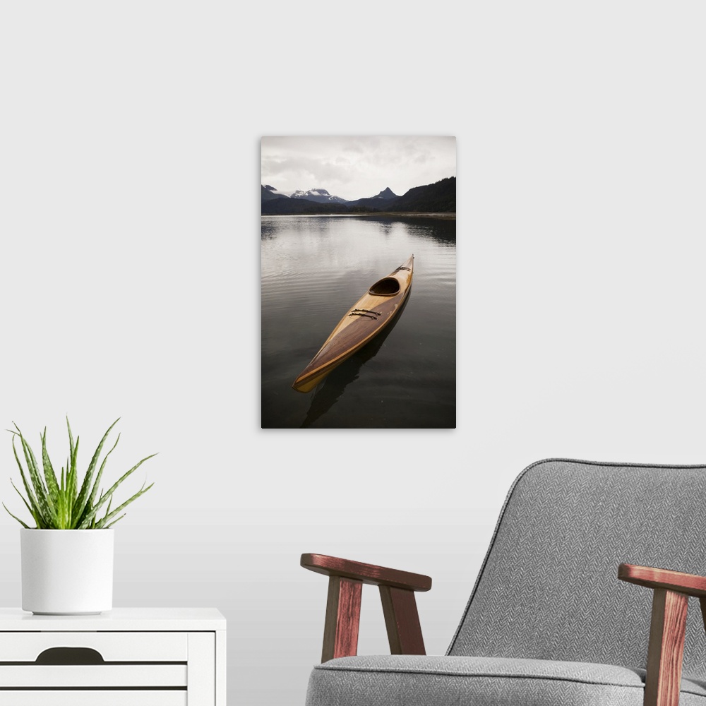 A modern room featuring A Wooden Kayak Sits On Tranquil Water With A View Of The Mountains In The Background, Kachemak Ba...