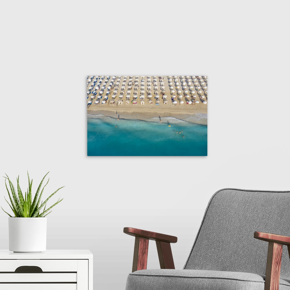 A modern room featuring An aerial view of Kathisma beach in Lefkada with people enjoying the deep blue waters.