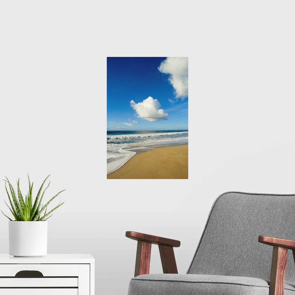 A modern room featuring Atlantic ocean waves break on the beach on a sunny day with clouds.