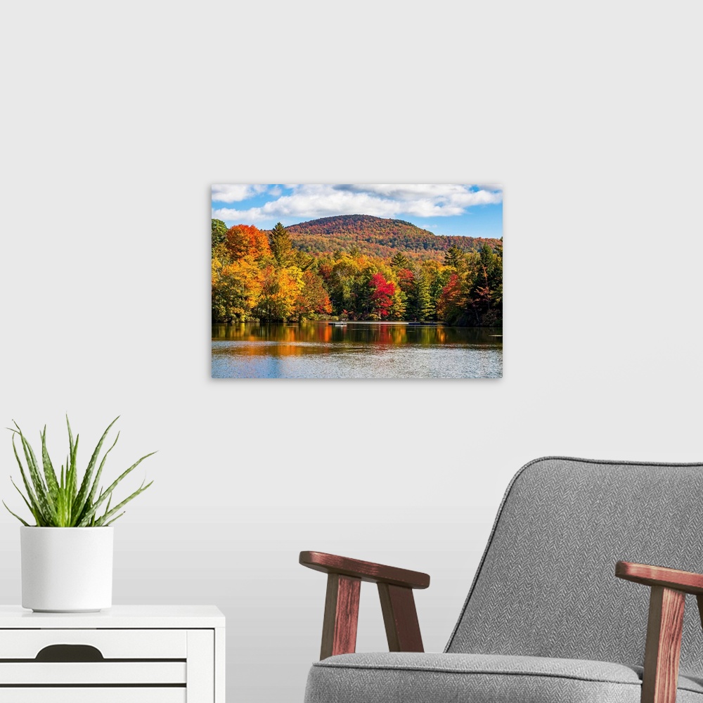 A modern room featuring Autumn coloured trees in a forest around a small lake, Sally's Pond, Quebec, Canada.