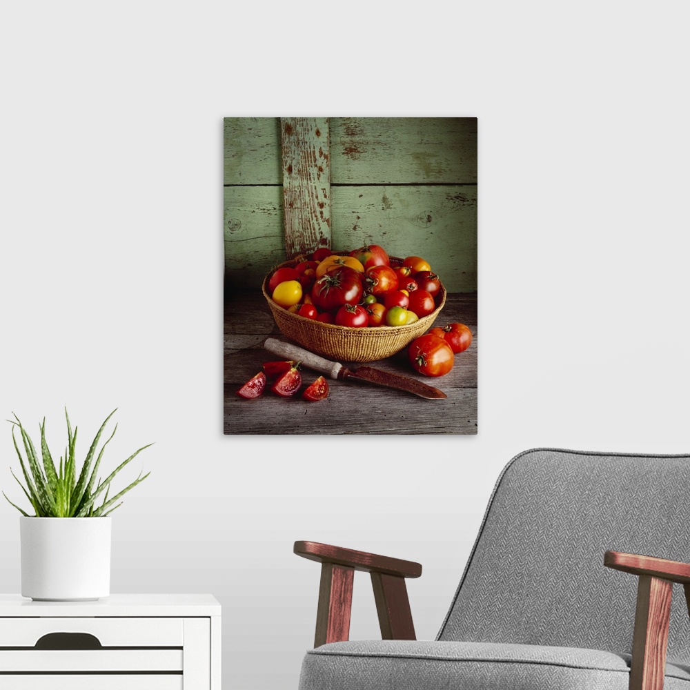 A modern room featuring Basket of heirloom tomatoes of various varieties with a slicing knife and sliced tomato
