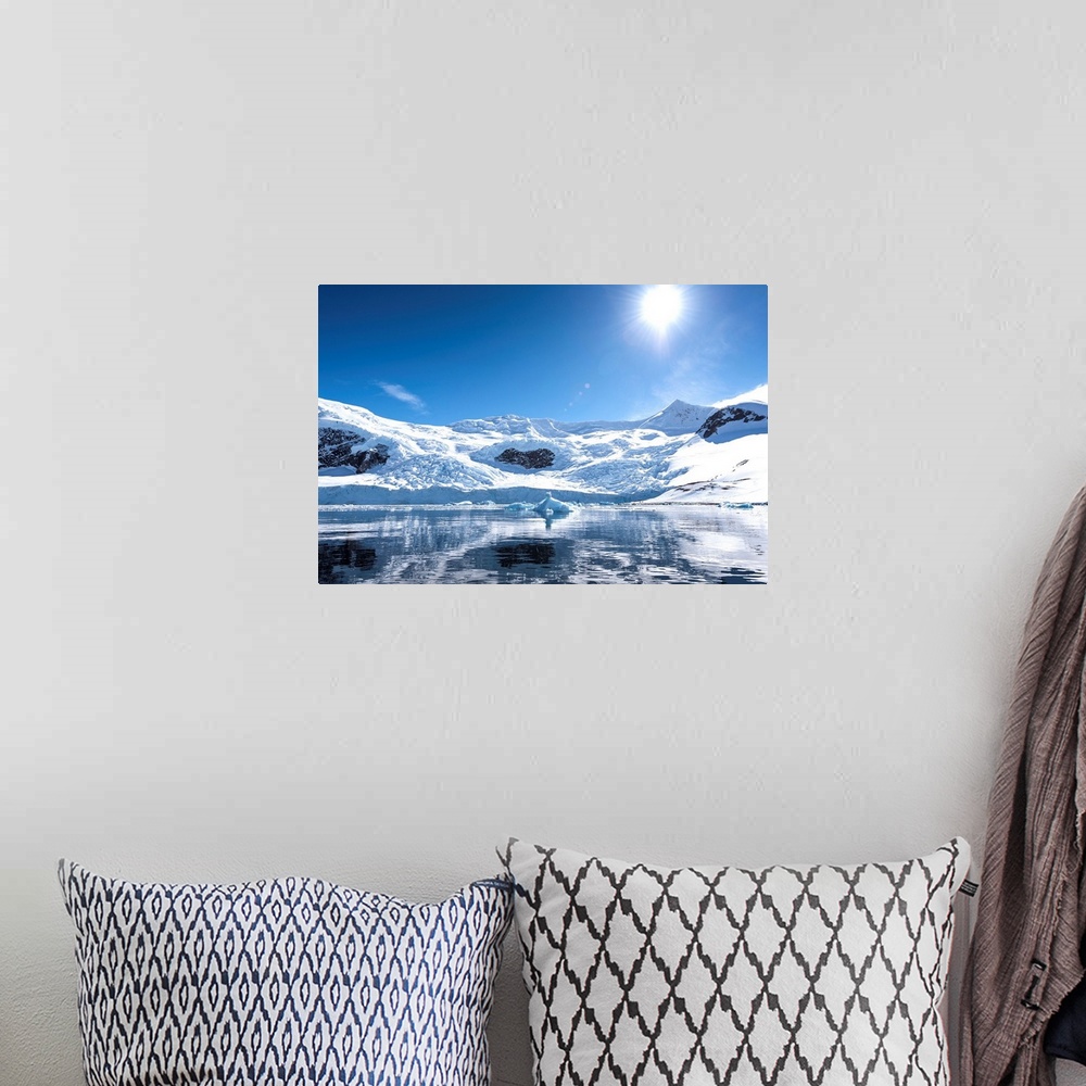 A bohemian room featuring Bright sun and snow on the mountains reflected in the water of Neko Harbor, Antarctica.