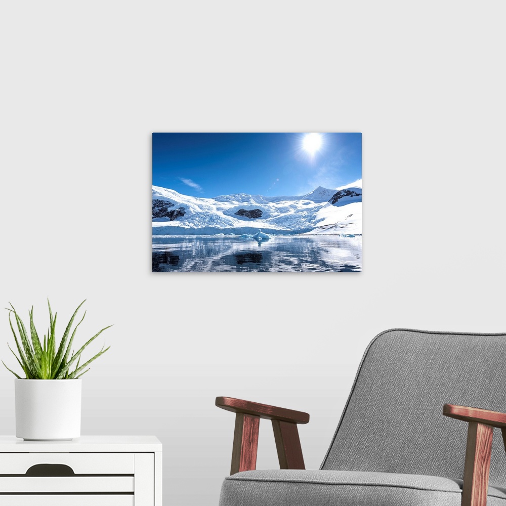 A modern room featuring Bright sun and snow on the mountains reflected in the water of Neko Harbor, Antarctica.