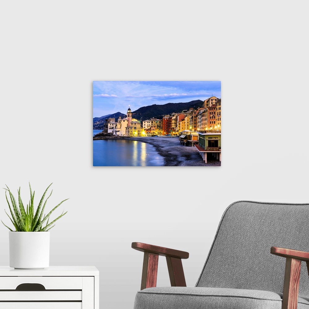 A modern room featuring Buildings illuminated by lights along the water's edge at sunrise, Camogli, Liguria, Italy.
