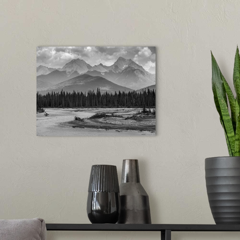 A modern room featuring Black and white landscape of the rugged Canadian rocky mountains with a forest and a flowing rive...