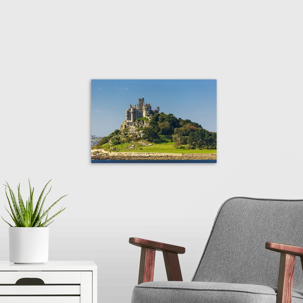 A modern room featuring Castle of St. Michael perched on top of a rocky hill along a shoreline, surrounded by trees with ...
