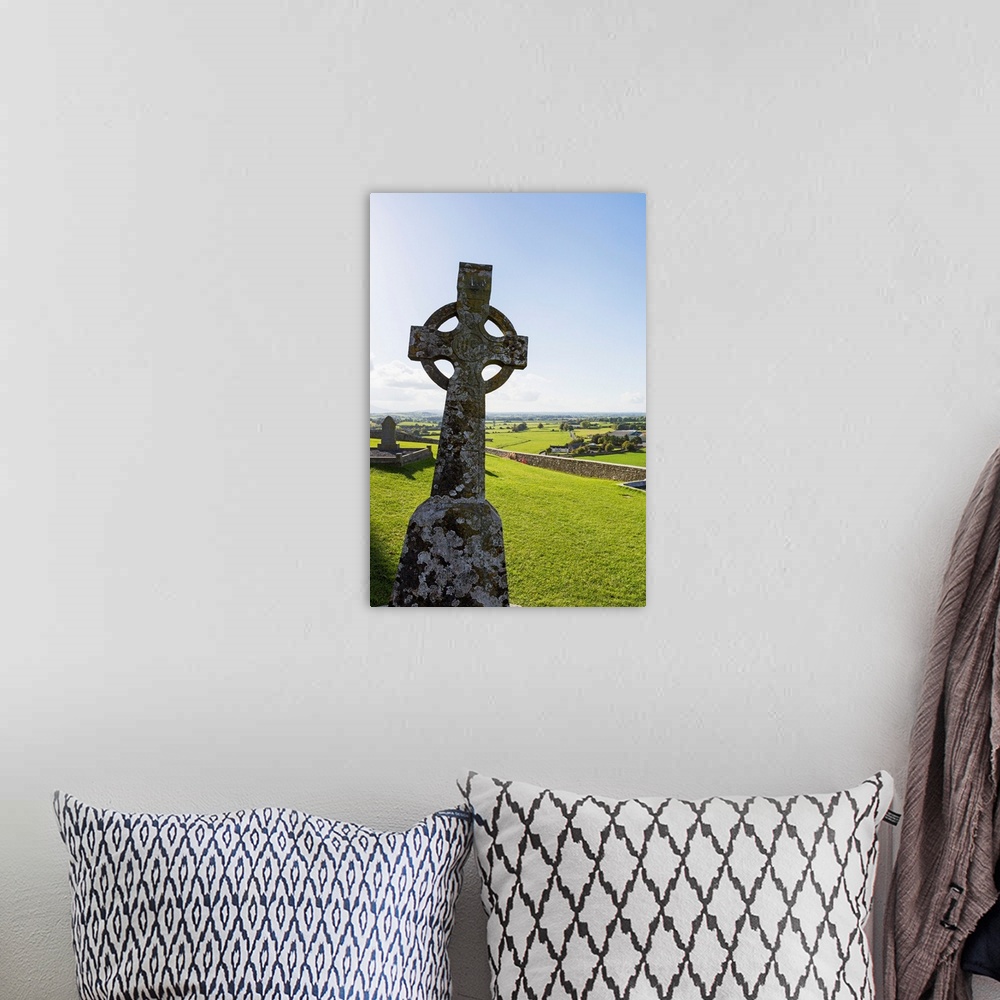 A bohemian room featuring Celtic cross on grassy hill with stone wall under blue sky, Cashel, County Tipperary, Ireland.