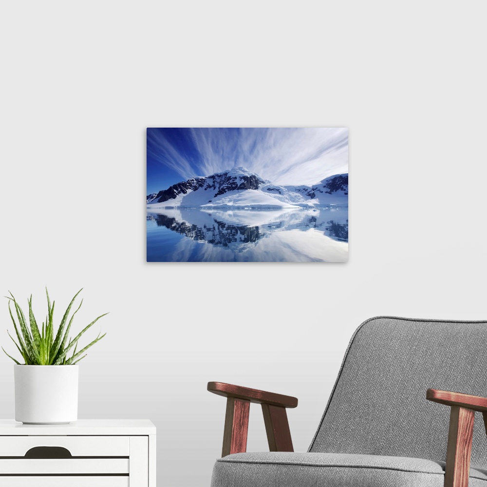 A modern room featuring Cirrus clouds over mountainous coast, and reflection in water.