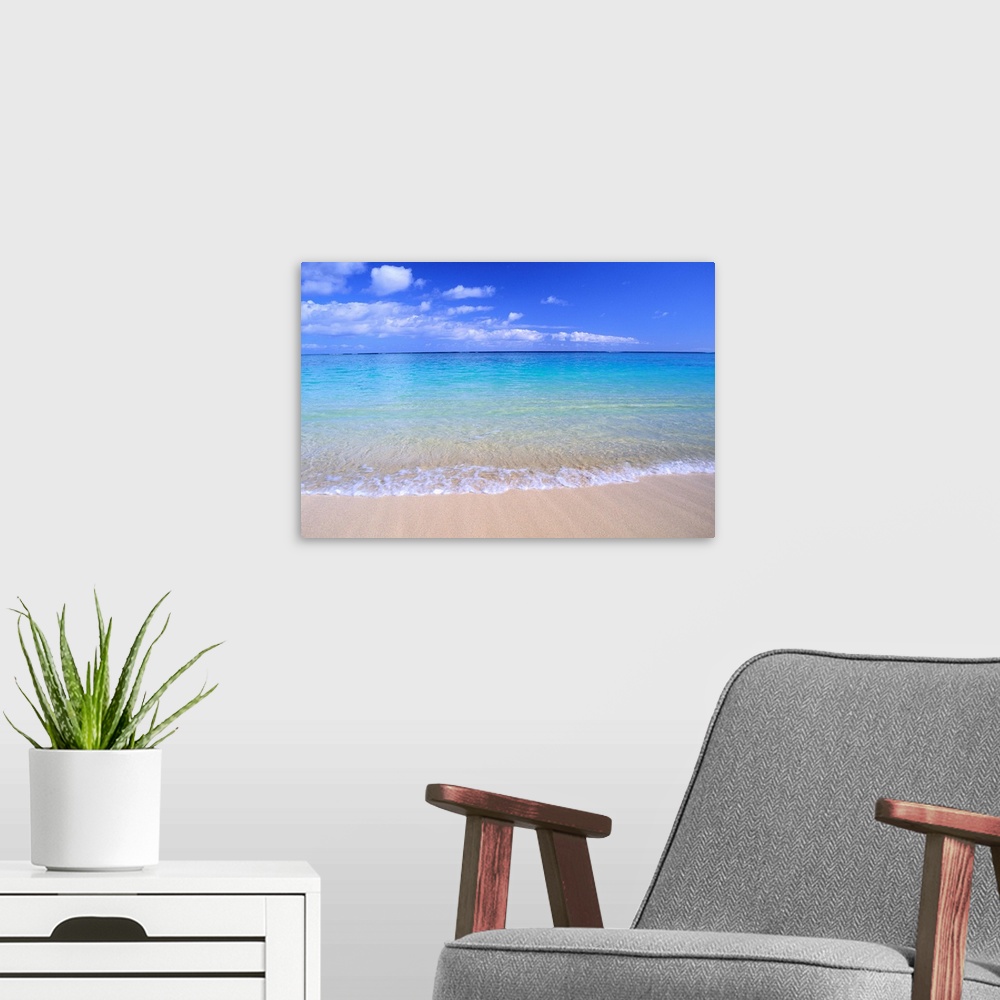 A modern room featuring This home docor features a photograph that is a horizontal seascape of clean ocean water washing ...